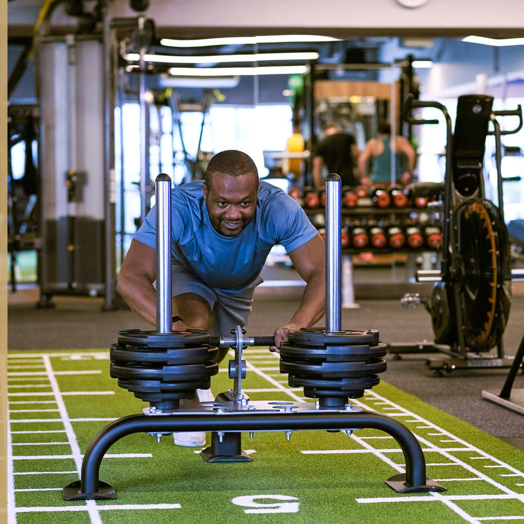 Image of man pushing sled in gym at Harbour Club