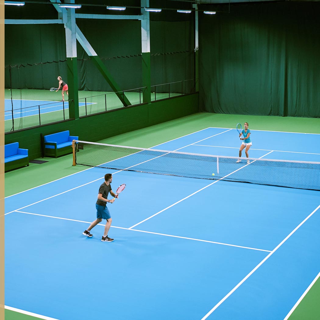 Image of man and woman playing tennis at Harbour Club
